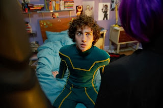 Dave, sentado en la cama, con su traje de Kick-Ass.