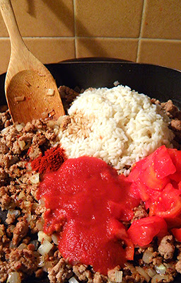 Ground meat, onion, rice, tomato sauce, tomatoes, and spices in frying pan