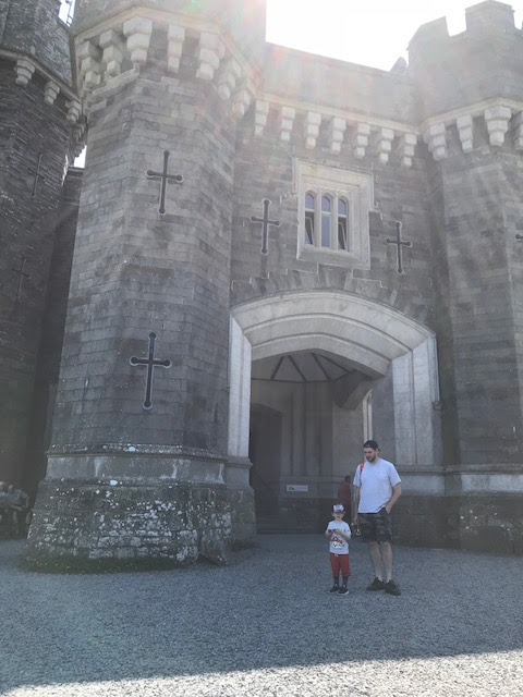 Father and little boy standing in front of a gothic style castle