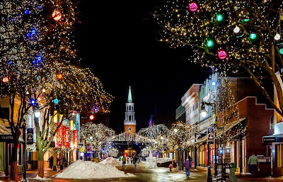 Immagine di una strada illuminata con le luci di Natale e una chiesa sullo sfondo