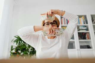 A woman holding money in front of her face, symbolizing the concept of earning money.