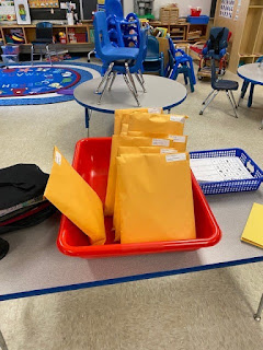 student yellow folder packets in a red bin