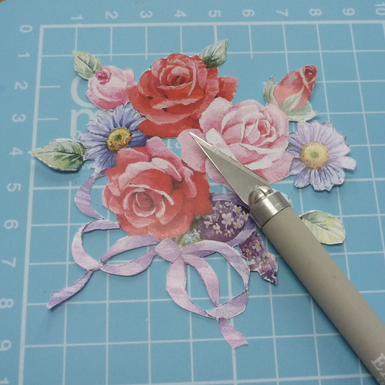 Cutting out white sections of printed design with a craft knife on a cutting mat