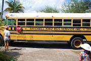 Bumping down the road in a worn out school bus with twenty or so other . (busservice )