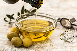 olive oil being poured into tiny glass container.