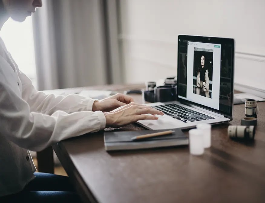 mujer-conmisa-blanca-sentada-frente-a-un-escritorio-operando-una-macbook-pro