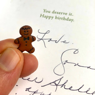 A small gingerbread man button in my hand, with Shelley's mom's card in the background.
