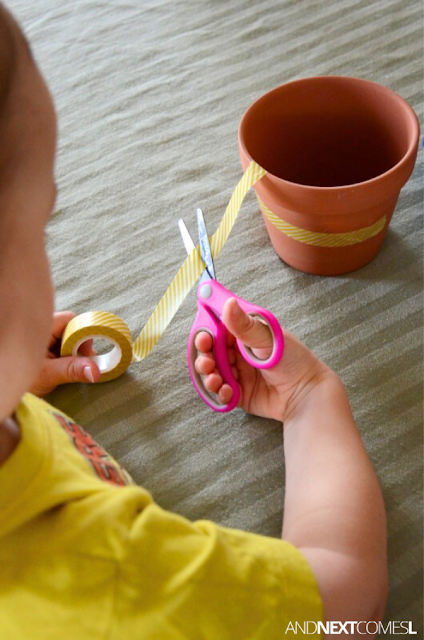 Close up of a toddler cutting yellow washi tape with scissors