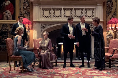 Movie still for Downton Abbey film where the Crawley family (including Penelope Wilton, Maggie Smith, Harry Hadden-Paton, Matthew Goode) sits around the fire having a drink