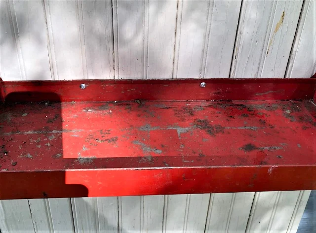 Photo of red metal garage tray screwed to a bead board cabinet door