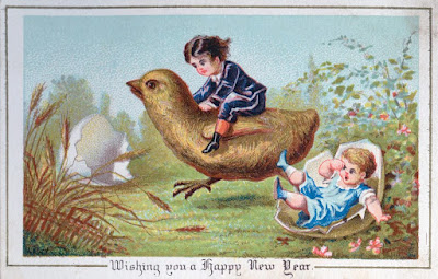 Victorian card with tagline "Wishing you a Happy New Year." Image features one little child in fancy blue clothing riding a giant chick, while another child (who has apparently fallen from or perhaps been knocked over by the charging chick steed) lies tumbled in half of a broken eggshell. The other half of the shell is lying in the background. The overall scene is of a garden or pastoral area.