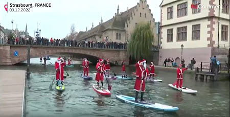 des personnes déguisées en père Noël faisant du stand-up paddle