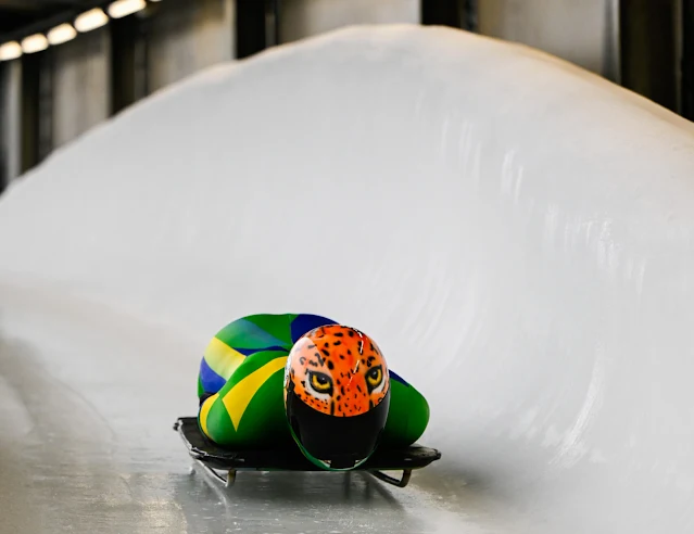 Nicole Silveira está de macacão vede e amarelo e capacete com a estampa do rosto de uma onça
