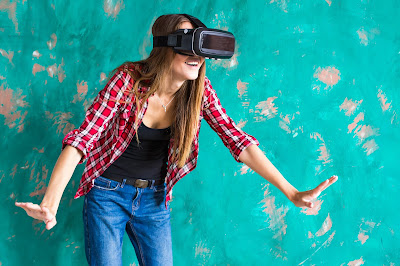 Pic of woman smilng and moving as she uses a virtual reality headset standing up