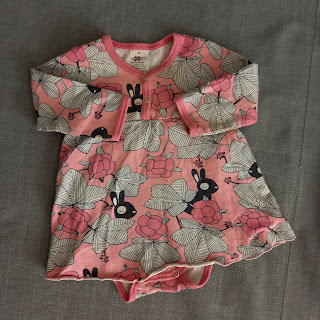 Vaaleanpunainen mekkobody, jossa kuviointina pupuja, lakan marjoja ja saman kasvin lehtiä.