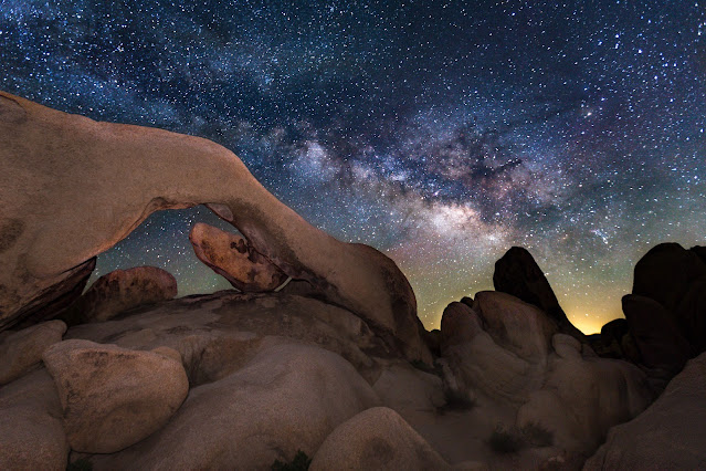 Nightime image of sandy desert rock formations under a canopy of stars