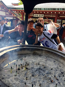 Teenage students in front of a large cauldron of incense at Senso-ji temple. People waft the fumes over their bodies to bestow good health - April 2015