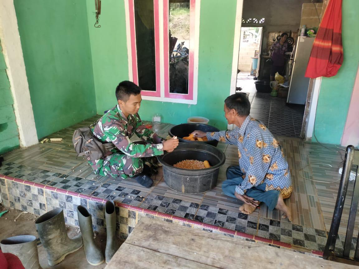 Keakraban Warga dengan Anggota Satgas TMMD Mengupas Jagung