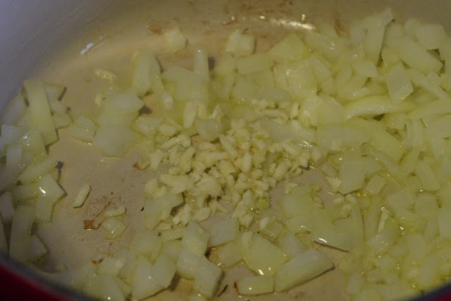 Garlic being added to the pot on the stove.