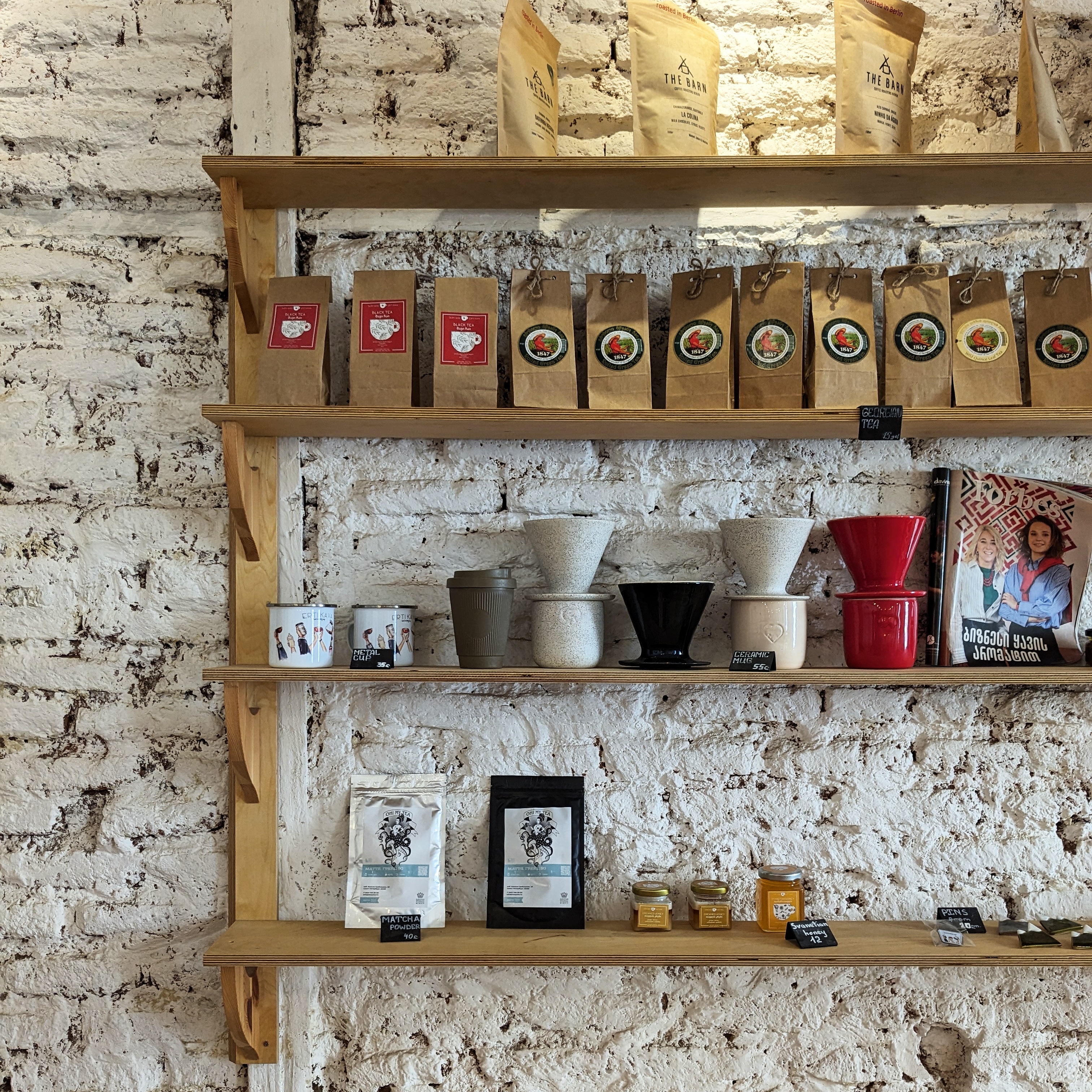 A wooden shelf filled with Coffee beans and cups for sale at Erti Kava Coffee Room, one of the best cafes in Tbilisi