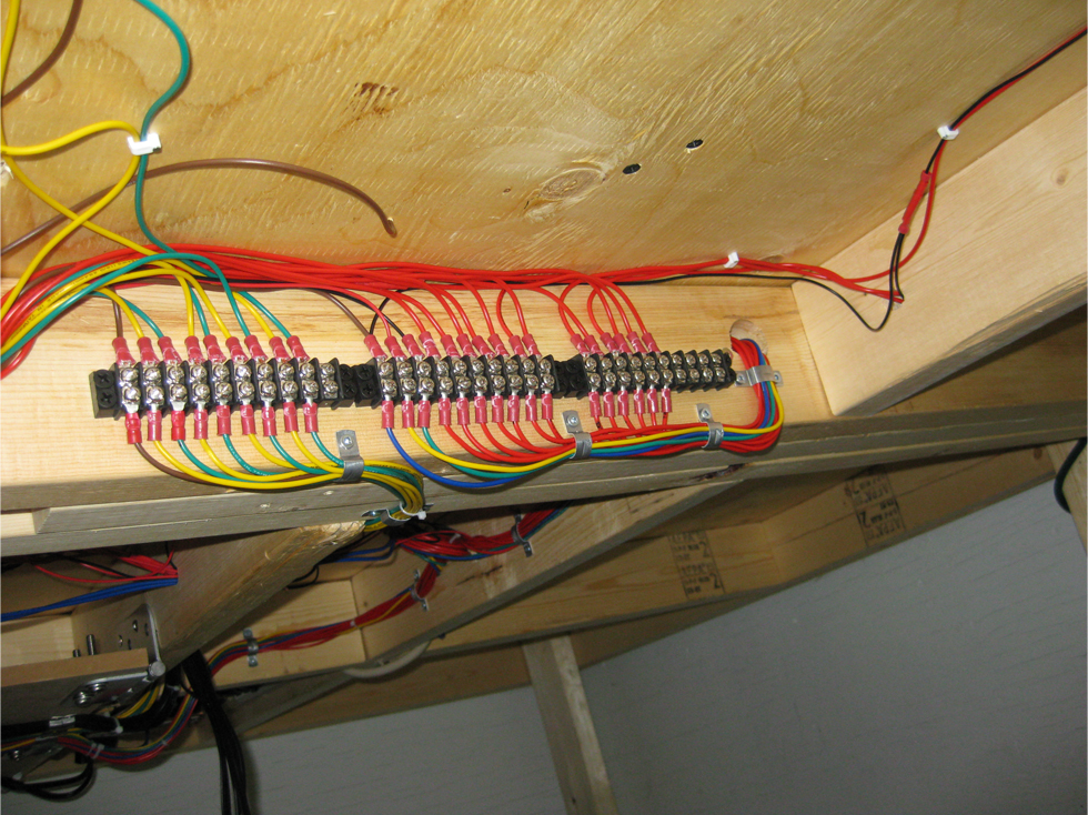 3 terminal strips installed in a row under model railroad benchwork with power leads attached to each terminal