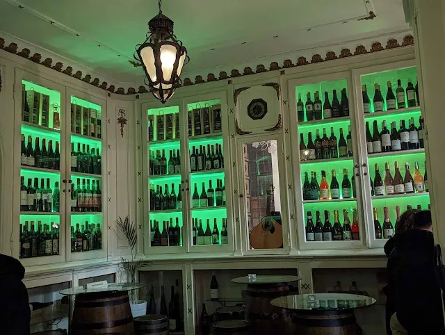 Green-backlit wine bottles at the Old Pharmacy in Lisbon
