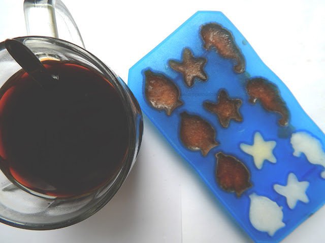 Cup of black coffee next to an ice cube tray filled with coffee and milk