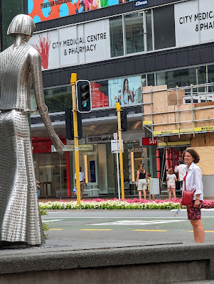 A woman on a busy Wellington shopping street looks at the Katherine Mansfield statue