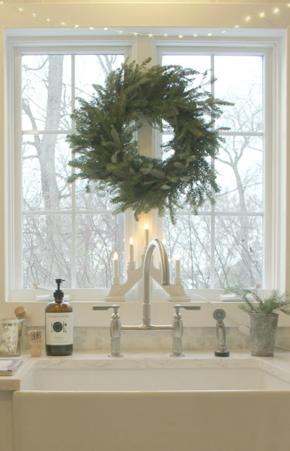 Fresh green holiday wreath on window above farmhouse sink