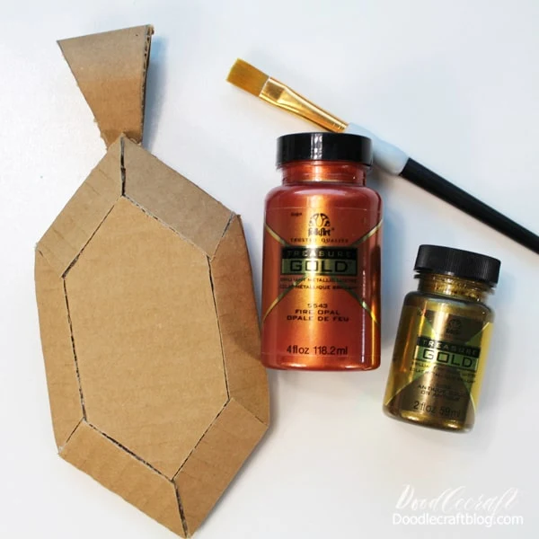 Step 5: Paint the Amulet   Now paint the cardboard amulet in a fabulous metallic paint. I used Treasure Gold Paint in Fire Opal and Antique Gold.