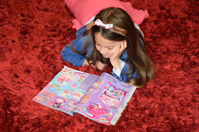 Smiling child looking at Shopkins in toy Smyths  catalogue