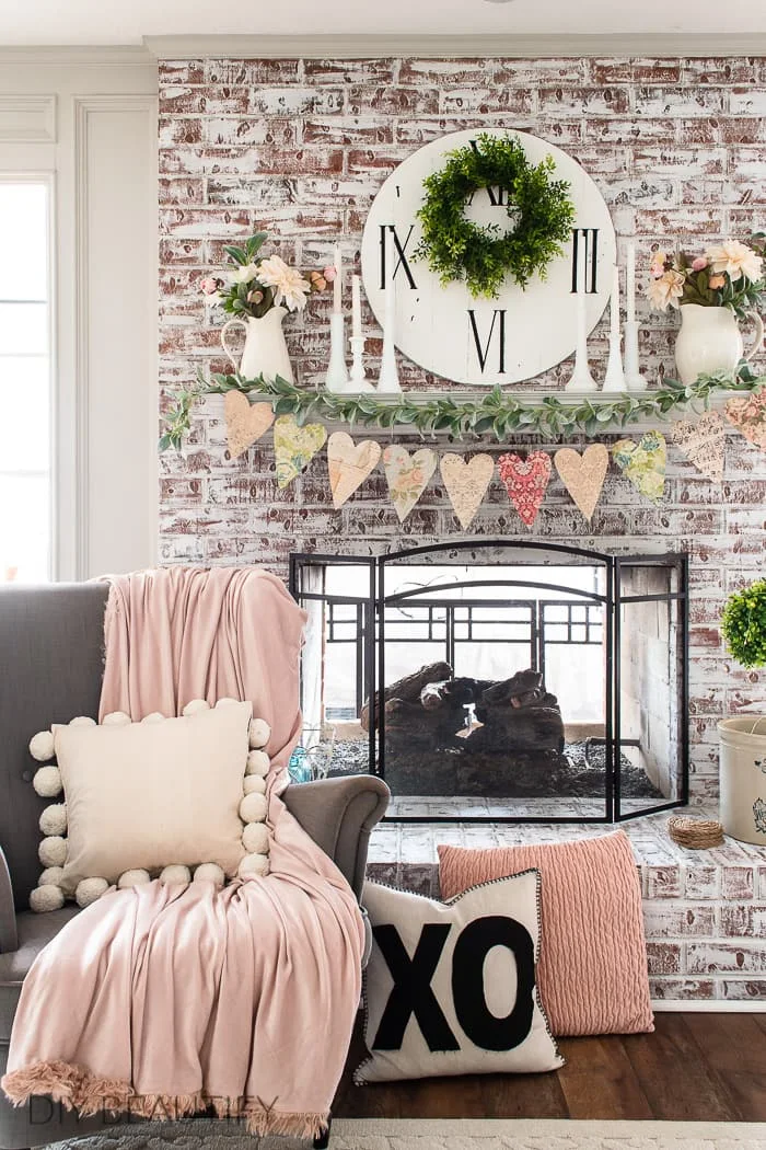 shabby chic fireplace mantel decorated for Valentine day with vintage heart garland, blush pink and milk glass