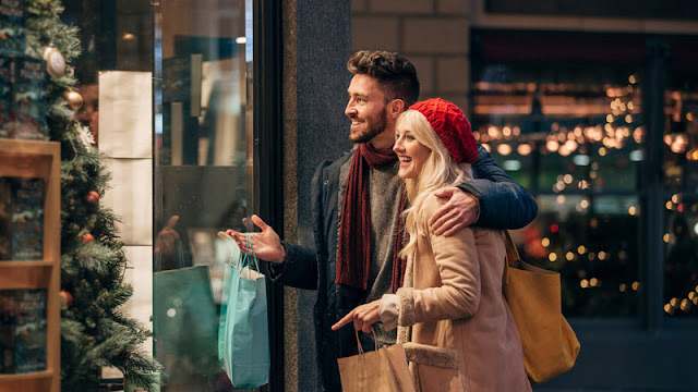 a couple holding shopping bags looking into a store window