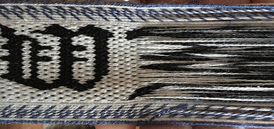 A photo of a section of tablet woven band with the weft removed for part of it