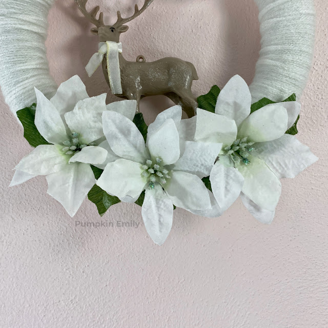 White flowers on a winter yarn wreath.