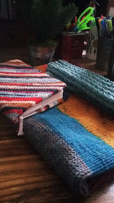 Three finished objects or knitting projects; a Strickplaner cover, a cowl and a pair of fingerless mitts.