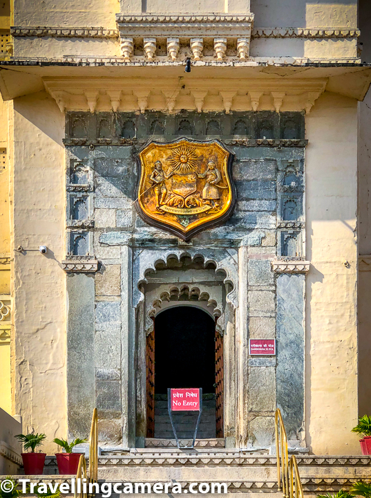 As you enter into the City Palace compound in Udaipur, you see huge open space and the palace on the right. Above photograph shows main door of the palace which is not used now. The podium in front of this door is used by the current custodian for various ceremonies which take place at Udaipur City Palace. Holika dahan, Ashva poojan etc take place in this part of the City Palace and custodian Shri Arvind Singh Mewar sit on the podium in front of this door to take care of all rituals of the day. This door is almost at the middle of City Palace building in Udaipur. On special occasions Shri Arvind Singh Mewar or his family members enter into the City Palace through this door as celebrations take place in the central court of the City Palace which is inside. This is outer side of the City Palace. Seating arrangements for evening light & sound show are also done in front of this door in Udaipur City Palace.