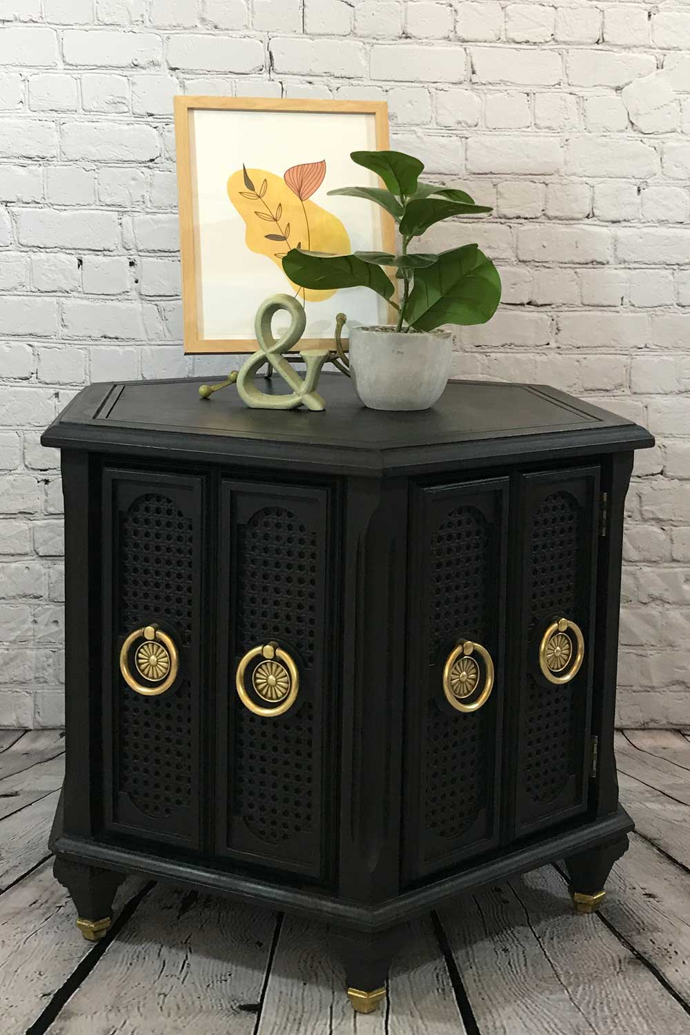 Finished black chalk painted vintage mid-century hexagonal end table with polished original hardware staged with plant and picture