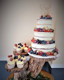 semi naked three tier wedding cake with fresh fruit and cupcakes 