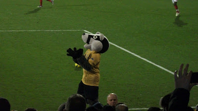 The mascot is a badger in a yellow shirt.