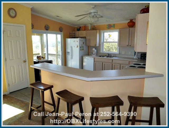 Enjoy the cool breeze as you whip up the best-tasting meals in this beautiful 6 bedroom canal front Corolla NC home for sale's kitchen lit by natural light.