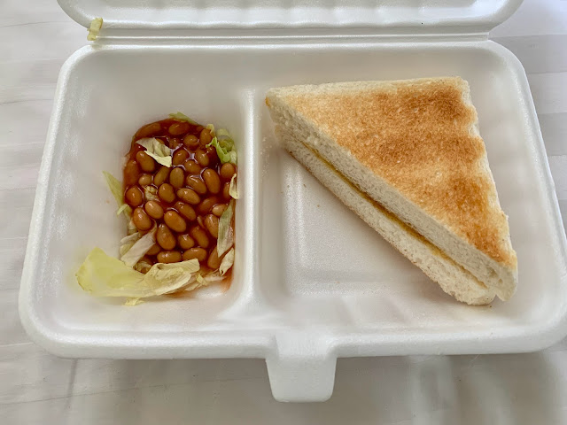 Styrofoam container with two slices of toast and baked beans