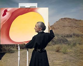 Georgia O'Keeffe holding her "Pelvis series" painting outdoors