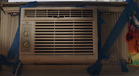 a window air conditioner perched precariously in a window