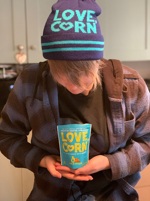 teen wearing LOVE CORN hat holding Love Corn packet