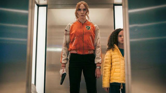 karen gillan with a gun and child in an elevator