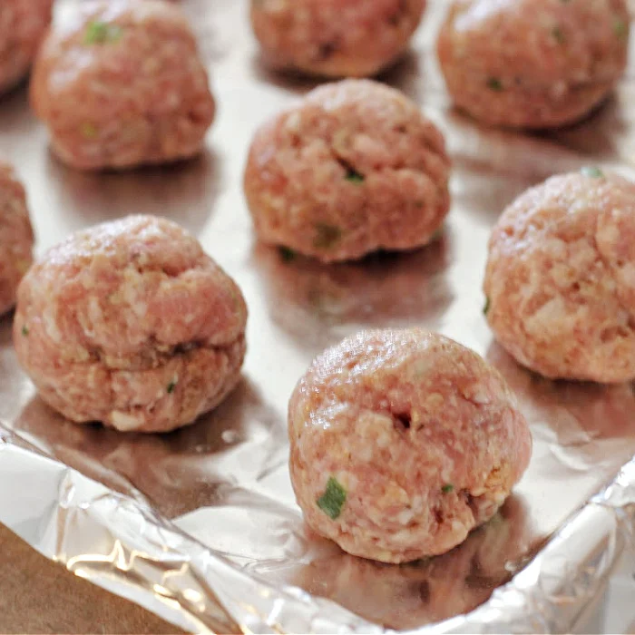 Raw Asian pork meatballs formed and ready for the oven on a sheet pan