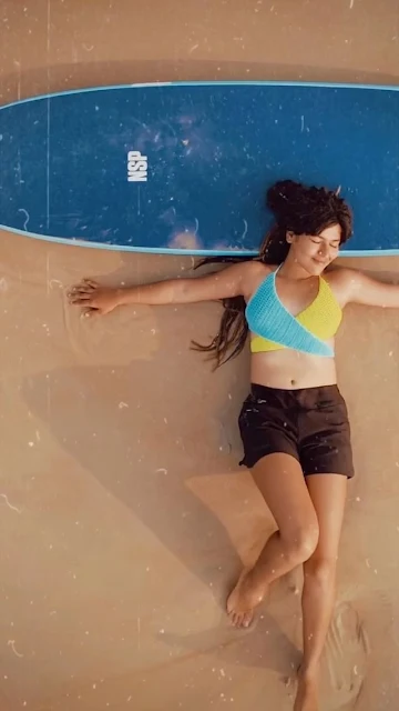 Nidhi Bhanushali laid down on beach with surfing board