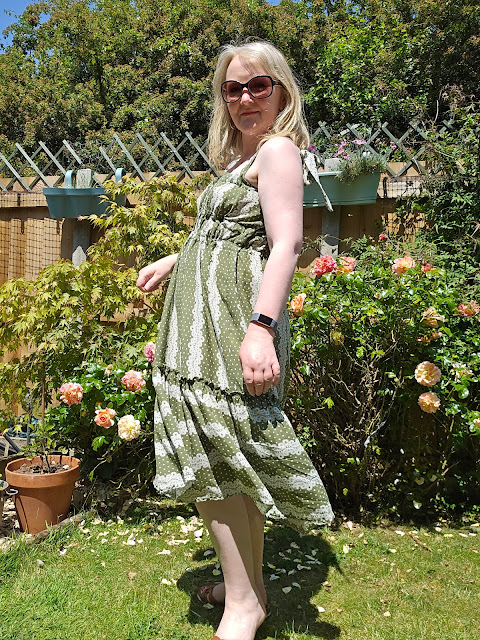 image of blonde/grey woman in sunglasses wearing olive green sundresses in garden