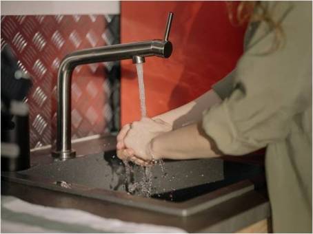 a woman washing her hands under a steady stream of water